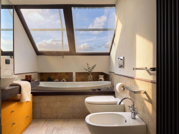 A compact bathroom with a skylight, a bathtub, a sink, and a toilet. - Attico Torlonia - Terrazzo in centro città (Roma)