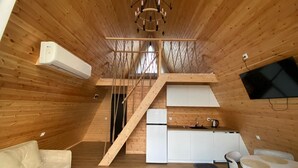 A compact, wooden interior with a kitchenette, a sofa, and a dining area.