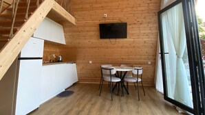 A wooden interior with a kitchen, dining area, and a staircase.