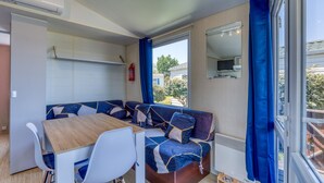 A compact living space with a dining table, seating area, and a window with curtains.