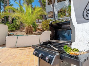 Ein Grill im Freien mit Bedienelementen und verschiedenen Speisen darauf.