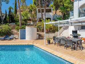 Ein Pool mit Fliesenrand, ein Barbereich mit Grill und Sitzgelegenheiten inklusive Stühle und Tisch.