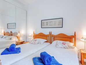 Ein Hotelzimmer mit zwei Betten, einem großen Spiegel und gerahmten Kunstwerken an der Wand.