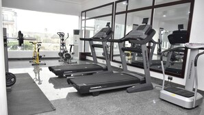 Un gimnasio con cintas de correr, una bicicleta estática y un banco para pesas.