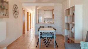 A modern kitchen with white cabinets, a dining table with chairs, and a clock on the wall. - Duplex with sea view (Adeje)