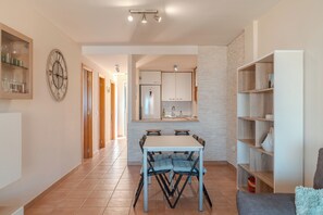 A modern kitchen with white cabinets, a dining table with chairs, and a clock on the wall. - Duplex with sea view (Adeje)