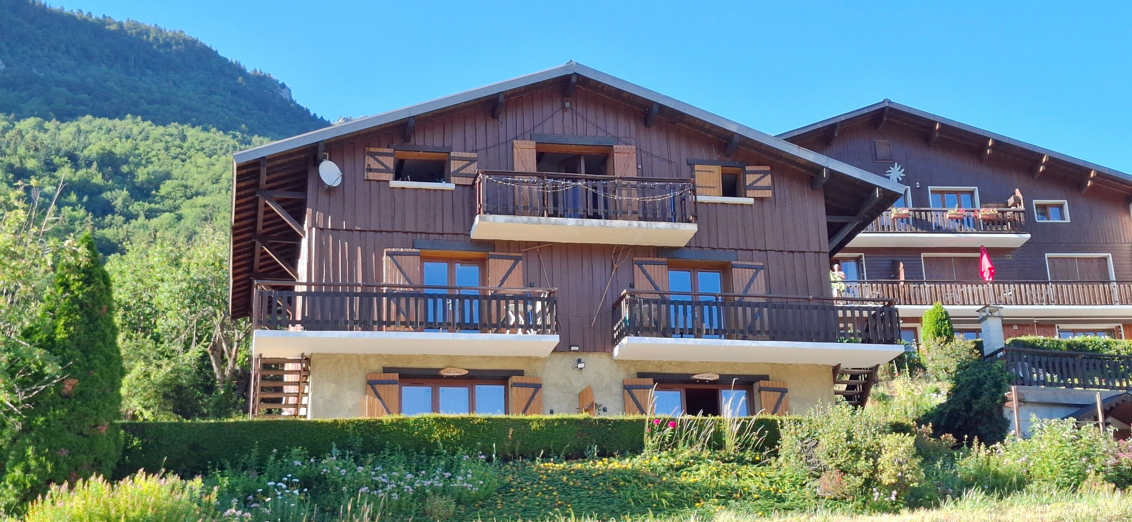 Un chalet en bois doté de balcons, d’une antenne parabolique et situé dans un cadre montagneux.