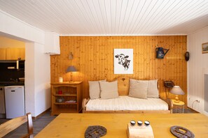 Une pièce chaleureuse avec un mur en bois, un lit, une petite table et un coin cuisine.