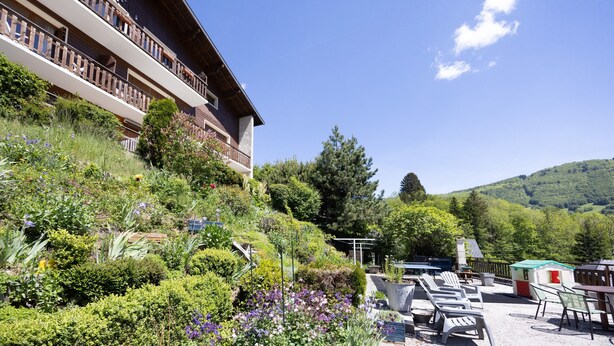 A hotel with a balcony, outdoor seating, and a garden.