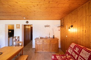 Um quarto com painéis de madeira, uma mesa de jantar de madeira, um banco, um sofá e um armário.