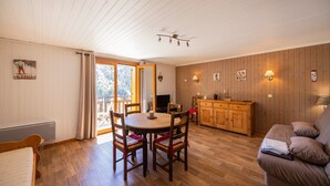 A room with a dining table, chairs, a sofa, a wooden cabinet, and a television. - “Le Skieur” Apartment with Mountain View, Balcony, and Wi-Fi (Aillon-le-Jeune)