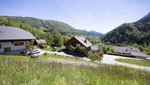 A rural village with traditional wooden houses, a clear sky, and lush green hills in the background. - “Le Skieur” Apartment with Mountain View, Balcony, and Wi-Fi (Aillon-le-Jeune)