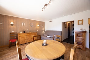Une pièce chaleureuse avec une table à manger en bois, des chaises, un canapé et un buffet.