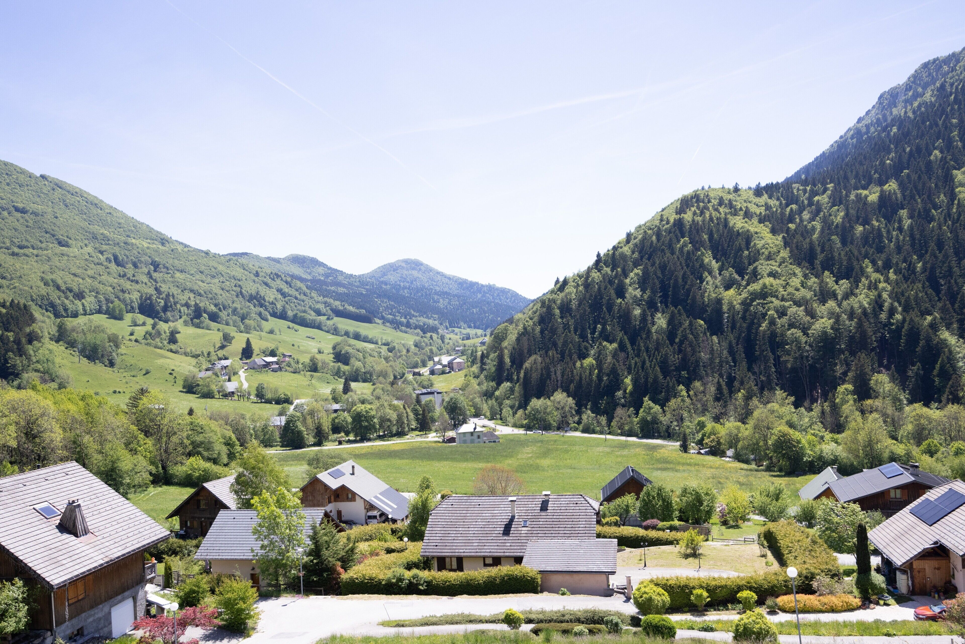 A rural village with traditional houses, a clear sky, and surrounding hills.