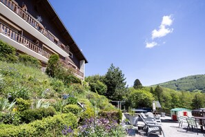 Et hotel med balkon, udendørs siddepladser og en have.