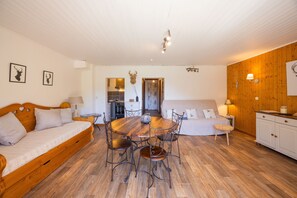 Ein gemütliches Zimmer mit Esstisch, einer Couch, einem Bett und einer Küchenzeile.