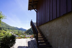 A building with a staircase leading to a balcony overlooking a valley. - Apartment "Les Cerfs" with Mountain View, Balcony, and Wi-Fi (Aillon-le-Jeune)