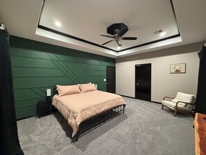 Ein Schlafzimmer mit Bett, Deckenventilator, Stuhl und Tür.