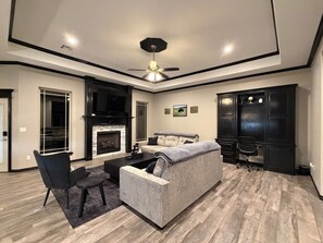 Een moderne woonkamer met een open haard, een bank, een salontafel en een plafondventilator.