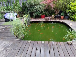 A wooden deck with a pond, surrounded by various potted plants and greenery. - A LOT OF CAHORS (Cahors)