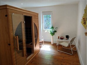 Una habitación con puerta corredera de vidrio, una mesita con una planta, una silla y una ventana.