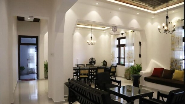 Una sala de estar moderna con una mesa de centro de vidrio, sillas negras, un sofá y un comedor con mesa y sillas.