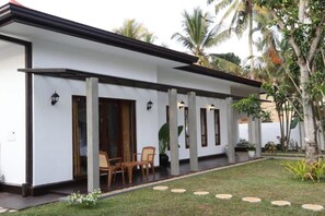 A modern building with a covered patio area, outdoor seating, and a well-maintained garden with palm trees. - Villa Amaara - 5 Bedrooms, large pool, private, in Kalutara, 100m from beach (Wadduwa)