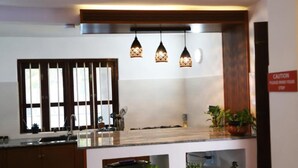 Una cocina moderna con una isla central, luces colgantes y un letrero de precaución.