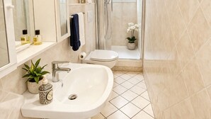 Une salle de bain moderne équipée d’un lavabo, de toilettes et d’une douche.