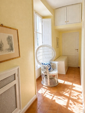 A hallway with a wicker chair, a white door, and a framed picture on the wall. - Dolce vita room center of Rome (Roma)