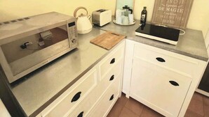 Une petite cuisine équipée d’un four à micro-ondes, d’un grille-pain, d’une bouilloire et d’un tableau noir servant de menu.