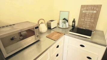 A kitchenette with a microwave, toaster, kettle, and a chalkboard menu.