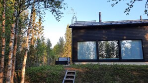 A modern house with large windows, a chimney, and a ladder leading to the entrance. - Villa Hulhavanhelmi (Syöte)