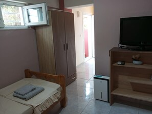A bedroom with a bed, a wardrobe, a television, and a small appliance.