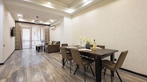 A hotel room with a dining area, a sofa, and a TV mounted on the wall. - Stay Inn on Yekmalyan  (Yerevan)
