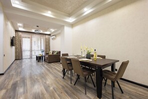 A hotel room with a dining area, a sofa, and a TV mounted on the wall. - Stay Inn on Yekmalyan  (Yerevan)