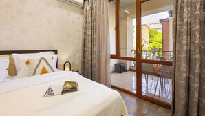 A hotel room with a bed, a nightstand, an air conditioning unit, a balcony with a table and chairs, and a view of the outside. - Stay Inn on Yekmalyan  (Yerevan)
