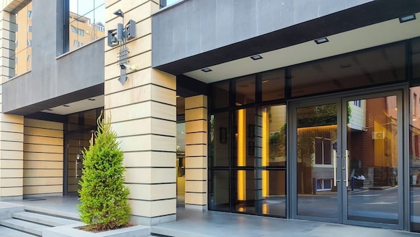 A modern building entrance with a glass door, a small green plant, and a set of steps leading up to the entrance. - Stay Inn on Yekmalyan  (Yerevan)