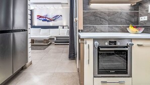 Una cocina moderna con horno Bosch, armarios blancos y una zona de estar con sofá y arte abstracto.
