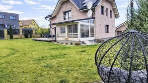 Una casa de dos pisos con techo inclinado, antena parabólica y un porche cubierto.