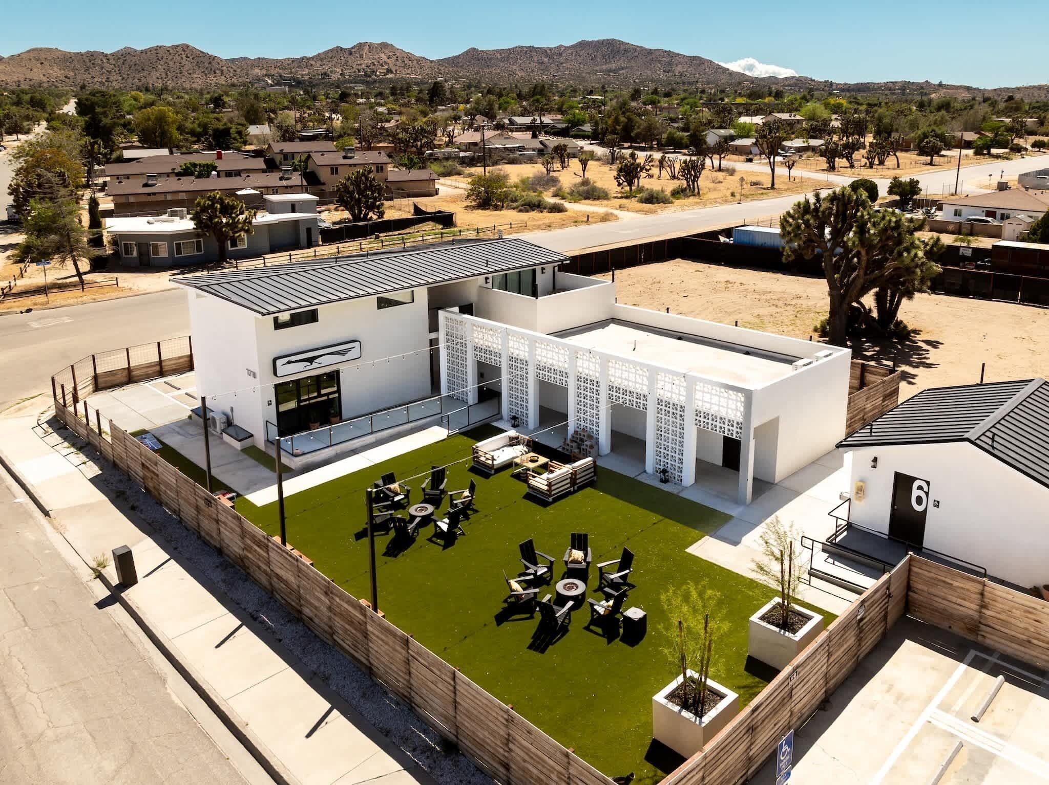 A modern building with a flat roof, a covered outdoor seating area, and a fenced courtyard.