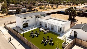 A modern building with a flat roof, a covered outdoor seating area, and a fenced courtyard.