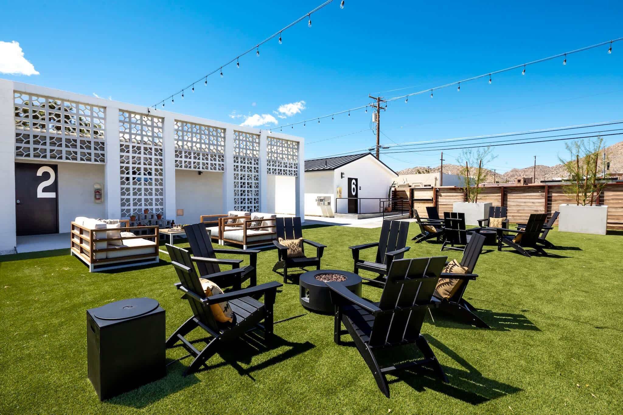A patio with outdoor seating, a fire pit, and a white building with numbered doors.