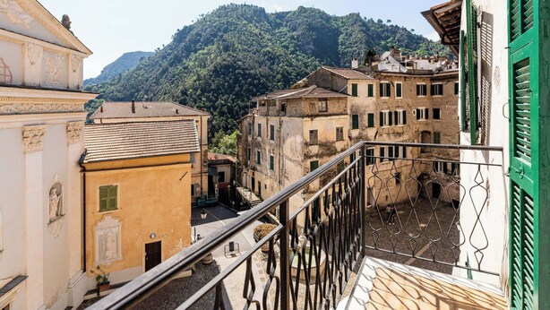 Ein Innenhof mit Gebäuden, einem Balkon und einem Berg im Hintergrund.