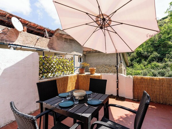 An outdoor patio with a table set for two, a large umbrella, and a view of a stone wall and greenery. - Beautiful private villa for 4 people with WIFI, terrace and pets allowed (Ventimiglia)