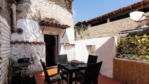 Una veranda con tavolo e sedie, un barbecue e un muro con decorazioni a griglia.