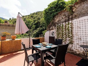 An outdoor patio with a table set for dining, surrounded by wicker chairs and a small round table. - Beautiful private villa for 4 people with WIFI, terrace and pets allowed (Ventimiglia)