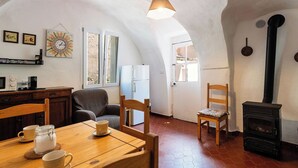 Una stanza accogliente con un tavolo da pranzo in legno, sedie, un divano, un camino e un angolo cottura con frigorifero e microonde.