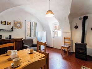 Una stanza accogliente con un tavolo da pranzo in legno, sedie, un divano, un camino e un angolo cottura con frigorifero e microonde.