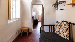 Un corridoio stretto con un letto, un tavolino e una finestra.